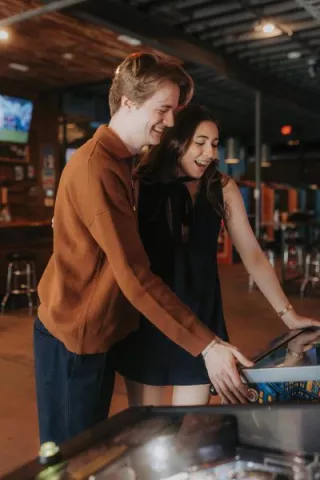 Olivia and Erik play arcade games in their engagement session with Caitlin & Camera