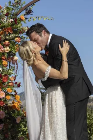 Bride and groom share kiss at the altar with flowers framing them