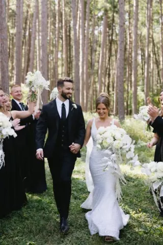 Bride and groom walk back down wooded aisle 