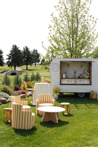 Sunny outdoor happy hour scene with yellow striped furniture and mobile bar at the Wexford at Emerald Greens