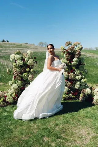 Model poses in front of enchanting altar comprised of monochromatic florals on the expansive grounds of Selmer + Stone