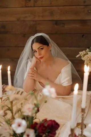 Model poses sat at staged reception table at Abbey Road Farms