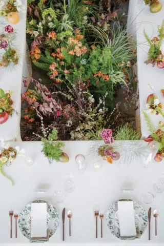 Organic florals in the middle of a rectangular table featuring simple, elegant design in glass house reception space at Woods & Co