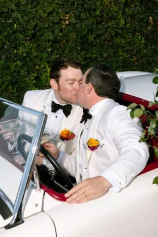 James and Timmy share a kiss in their floral decorated vintage getaway car