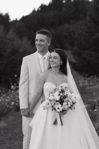 Bride and groom stand side by side with scenic views of Youngberg HIll & Winery in the background, black and white