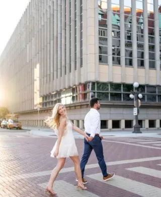 Katie and Zachary cross a street in Downtown St. Paul in their engagement photo session 