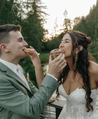 Bride and groom feed each other donuts at outdoor reception