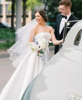 Meredith and Daniel enter their vintage getaway car in their wedding day attire