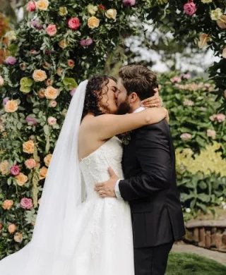 Valeria and Benjamin share a kiss at their floral-filled altar at Kiana Lodge