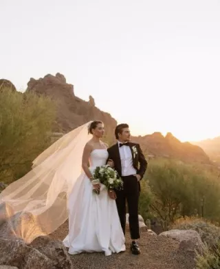 Bride and groom pose on the rocks of Camelback Mountain with the golden hour casting a glow behind them
