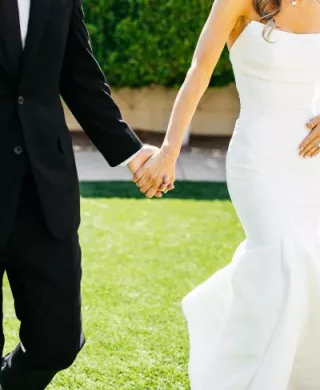Bride and groom holding hands against the grounds of Omni Scottsdale Montelucia