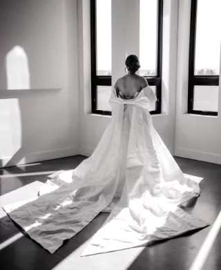 Black and white photo of model wearing gown with bow detail shawl 