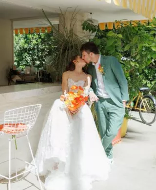 Bride and groom share a kiss sitting outside at their sunny wedding day at Parker Palm Springs