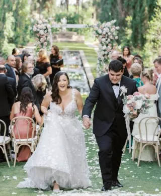 Samantha and Ryan cheer as they walk back down the floral-lined aisle at Sierra Madre