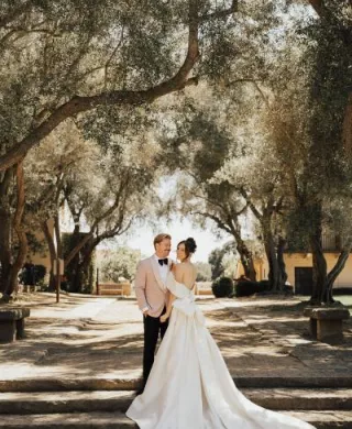 Bride and groom smile and pose, framed by trees on the grounds of The Cate School