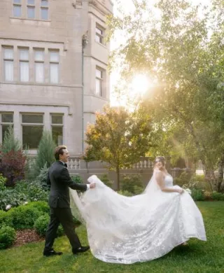 Jackson holds Grace's train as they walk across the grounds of American Swedish Institute