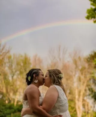 Couple shares a kiss under a rainbow