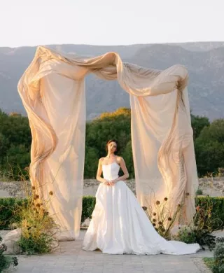 Model poses under architectural and organic altar against mountainous landscape at Topa Vista