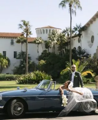 Cristabel and Martin pose in their vintage getaway car outside of the Santa Barbara Courthouse