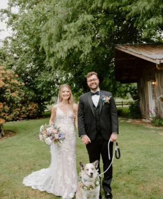 Bride and groom pose with their dog on their wedding day at Woodland Meadow Farms