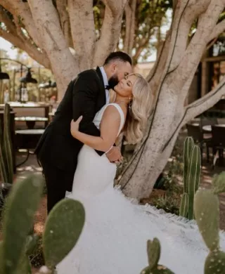Bride and groom share romantic embrace framed by cacti