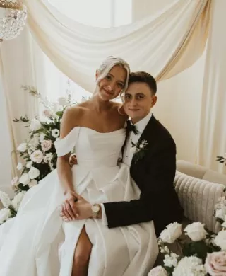 Bride sits on groom's lap in romantic lounge vignette on wedding day at Woodhaven