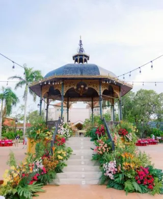 Bright and lush tropical florals line the steps of a gazebo in multicultural wedding in cancun
