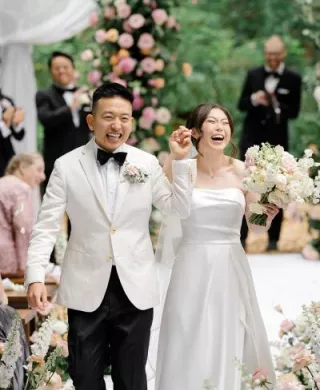 Bride and groom hold hands and cheer with joy while walking down aisle after outdoor wedding ceremony at Twin Willow Gardens