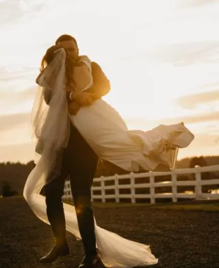 Connor picks up and twirls Katie on the grounds of Fiddler's Bluff on their wedding day