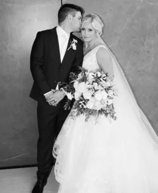 Groom kisses side of bride's head as they pose for their couple portrait outside of Venue 5 Twenty-Two