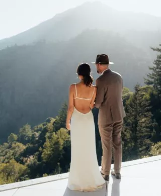 Bride and groom look out onto mountainous landscape 