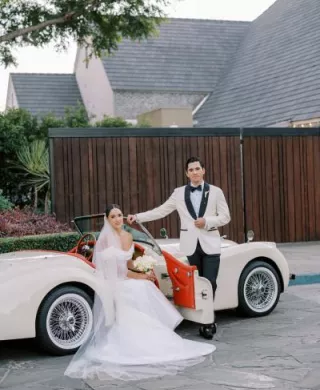Olivia and Blaec pose in a vintage getaway car