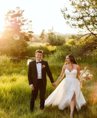 Bride and groom walk hand in hand in the golden hour light on the grounds of Sunriver Resort