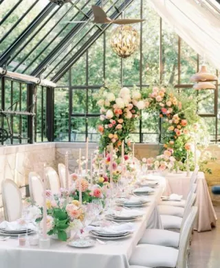 Greenhouse reception dinner featuring designer tableware and lush florals