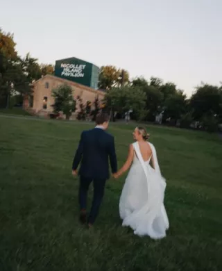 Abby and Caleb walk on the grounds of Nicollet Island Pavilion on their wedding day