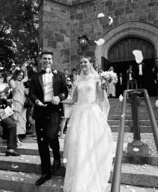 Isabel and John descend the staircase after ceremony t Plymouth Congregational Church as petals waft through the air