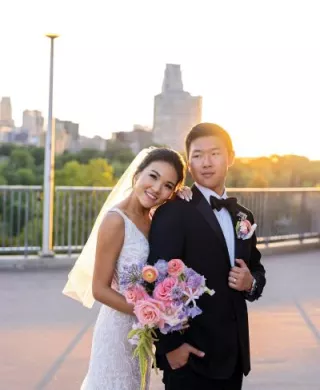 Bride and groom embrace with bright whimsical florals in hand