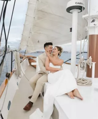 Groom holds bride in his arms on a sailboat for their welcome party