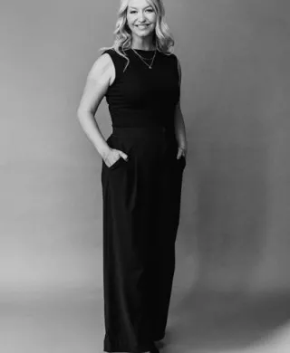 Headshot of Arizona Bride publisher Brittany O'Neill, standing wearing all black, smiling with hands in pockets
