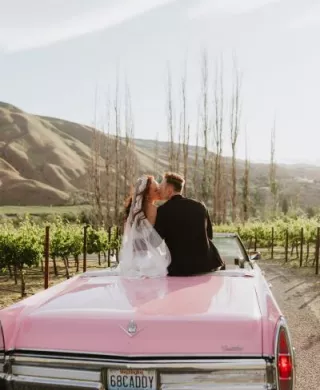 Lauren and Braedon share a kiss as they sit in a classic pink cadillac convertible