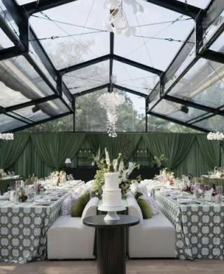 Bold maximalist reception design featuring luxe green draping and textured chandeliers at Woodland Glasshaus