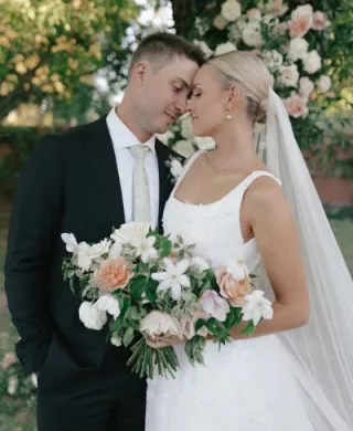 Bride and groom stand with foreheads pressed together, the bride holding her bouquet at their outdoor wedding day