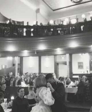 Caitlin and Josh Sharing their First Dance with Friends and Family Watching from the Balcony of The Grand Event Center