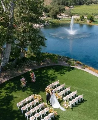 Aerial scene of models walking down aisle in outdoor ceremony featuring peachy florals on the grounds of Monserate Winery