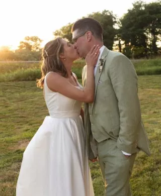 Bride and groom share a kiss during golden hour-lit reception at Hawk Creek Gallery