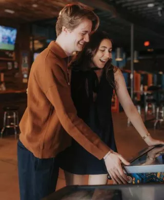 Olivia and Erik play arcade games in their engagement session with Caitlin & Camera