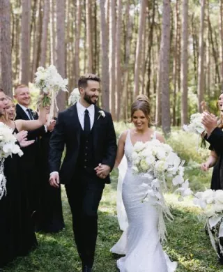 Bride and groom walk back down wooded aisle 