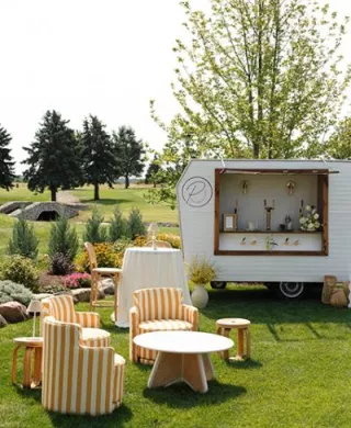 Sunny outdoor happy hour scene with yellow striped furniture and mobile bar at the Wexford at Emerald Greens