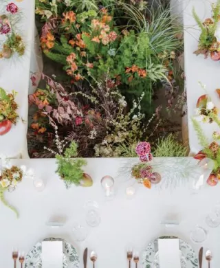 Organic florals in the middle of a rectangular table featuring simple, elegant design in glass house reception space at Woods & Co