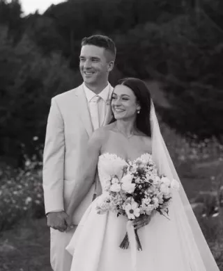 Bride and groom stand side by side with scenic views of Youngberg HIll & Winery in the background, black and white